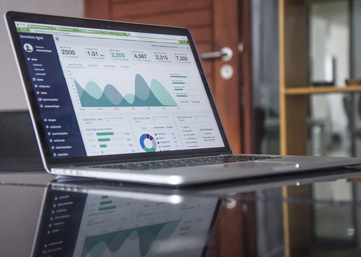 A laptop showing charts and analytics on a wooden desk